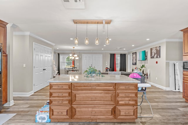 kitchen featuring a breakfast bar, light stone countertops, a center island, and hanging light fixtures