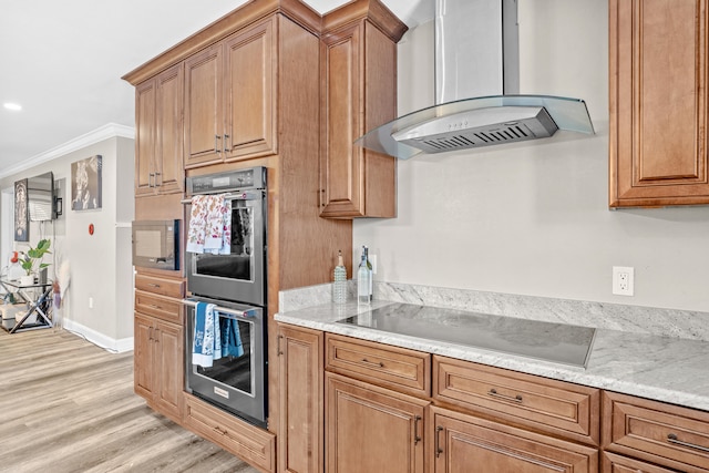 kitchen with light wood-type flooring, ornamental molding, black electric cooktop, double oven, and wall chimney range hood