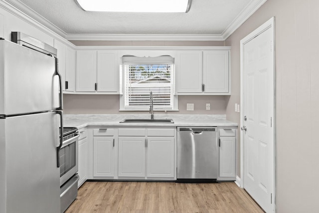 kitchen with stainless steel appliances, white cabinetry, ornamental molding, and sink