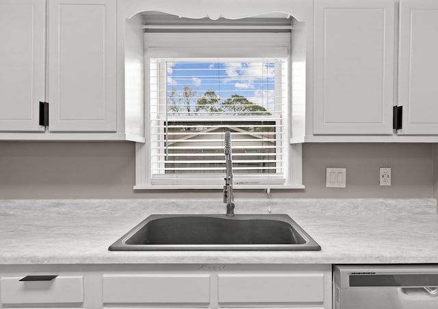 kitchen with dishwashing machine, sink, and white cabinets