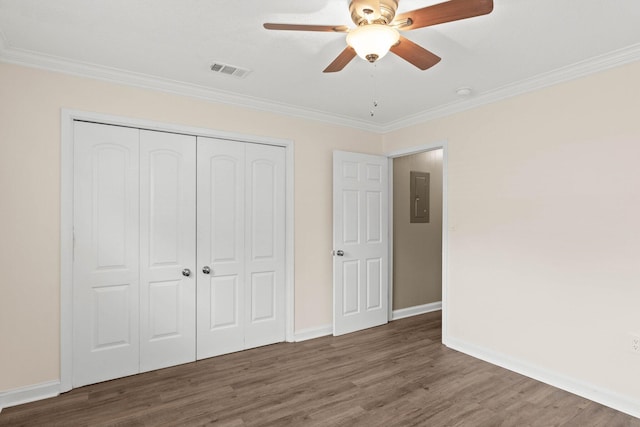 unfurnished bedroom with ceiling fan, dark wood-type flooring, electric panel, crown molding, and a closet