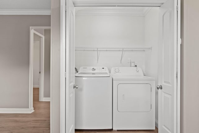 laundry room with hardwood / wood-style floors, washing machine and dryer, and crown molding