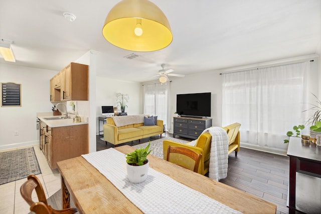 dining area with sink, light hardwood / wood-style floors, and ceiling fan