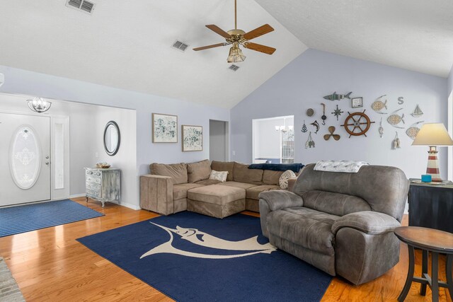 living room featuring lofted ceiling, hardwood / wood-style floors, and ceiling fan with notable chandelier