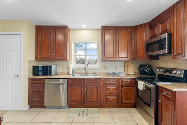 kitchen featuring stainless steel appliances, sink, light tile patterned floors, a textured ceiling, and tasteful backsplash