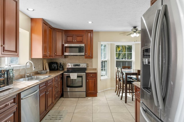 kitchen with tasteful backsplash, appliances with stainless steel finishes, sink, ceiling fan, and light tile patterned floors