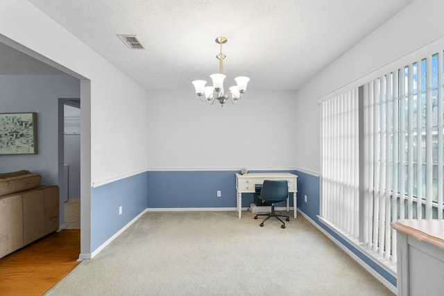 carpeted home office with a textured ceiling and an inviting chandelier