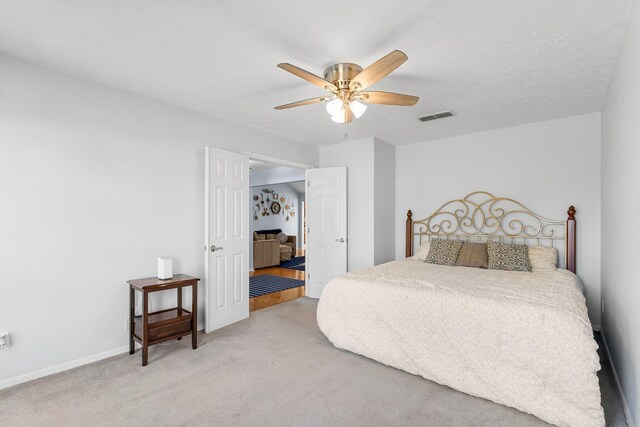 carpeted bedroom with ceiling fan and a textured ceiling