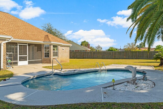 view of pool featuring a yard, a patio area, and a sunroom