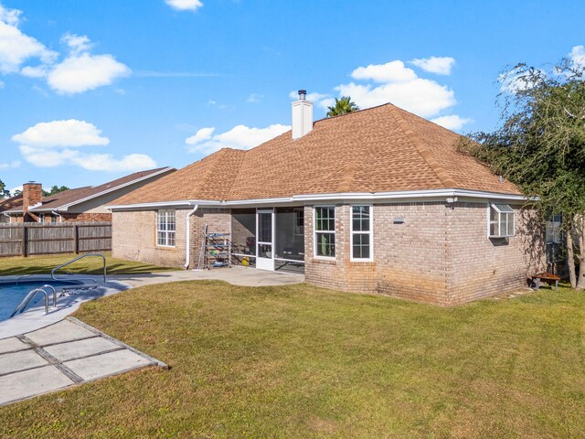 rear view of house featuring a patio, a lawn, and a sunroom