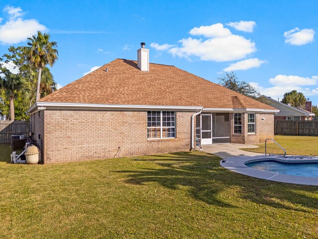 rear view of house with a fenced in pool, a patio area, a yard, and a sunroom