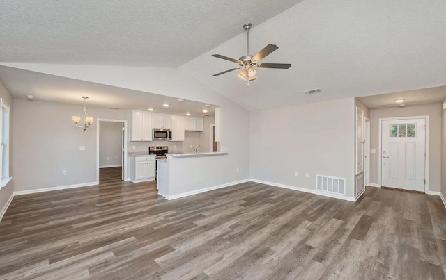 unfurnished living room with vaulted ceiling, ceiling fan with notable chandelier, and dark hardwood / wood-style floors