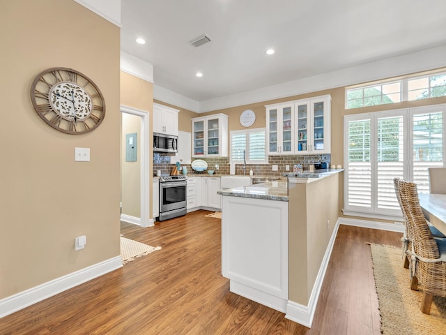 kitchen featuring white cabinets, stainless steel appliances, a wealth of natural light, and hardwood / wood-style flooring