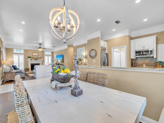 dining space with hardwood / wood-style floors and ceiling fan with notable chandelier