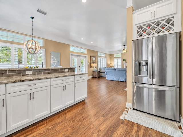 kitchen with white cabinets, light stone countertops, decorative light fixtures, light hardwood / wood-style floors, and stainless steel fridge with ice dispenser