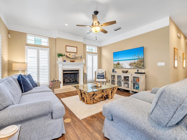 living room with hardwood / wood-style flooring, ceiling fan, and ornamental molding