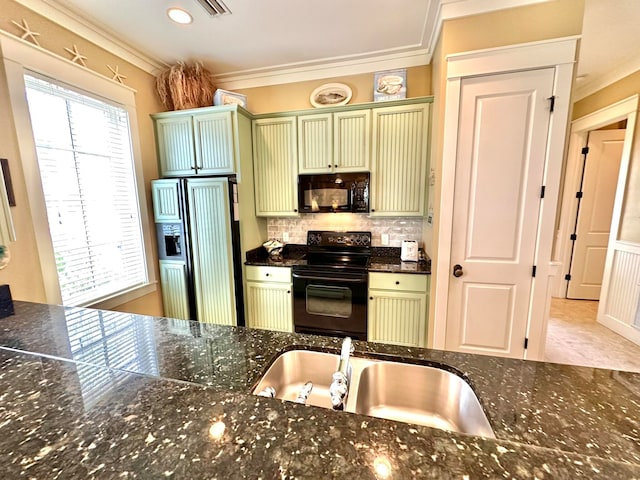 kitchen with black appliances, ornamental molding, dark stone counters, green cabinetry, and sink