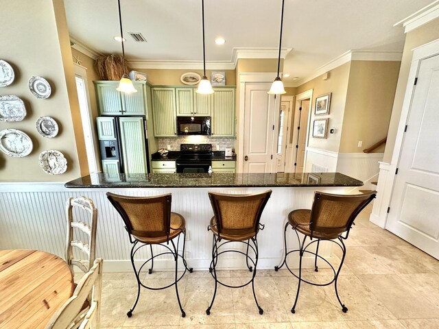 2450 Bungalo Ln, Miramar Beach, FL 32550 - kitchen with black appliances, ornamental molding, a kitchen bar, tasteful backsplash, and a wainscoted wall