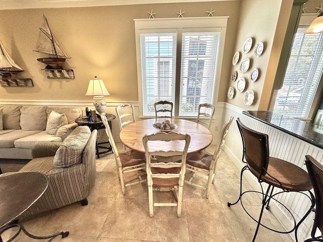 2450 Bungalo Ln, Miramar Beach, FL 32550 - dining space with wainscoting, a decorative wall, and light tile patterned flooring