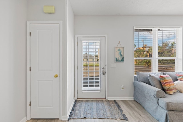 doorway to outside featuring a textured ceiling and light hardwood / wood-style floors