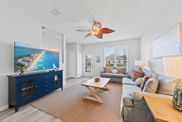 living room featuring light hardwood / wood-style floors, a textured ceiling, and ceiling fan