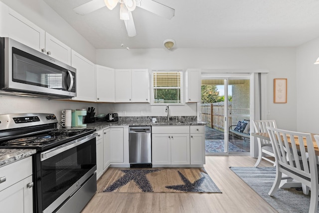 kitchen with appliances with stainless steel finishes, white cabinets, and light hardwood / wood-style floors