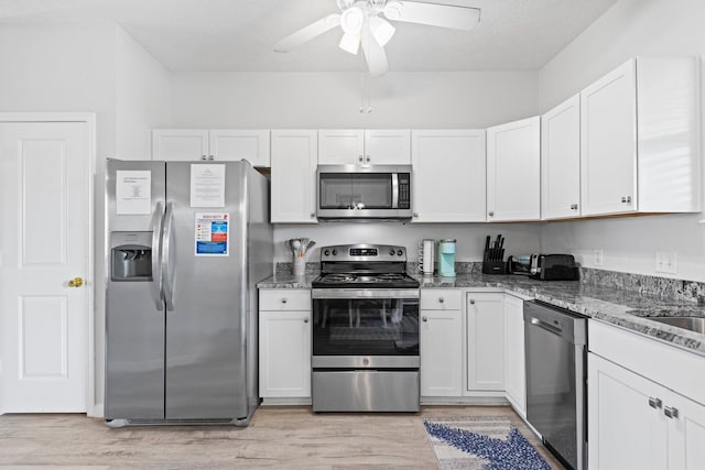 kitchen featuring white cabinetry, light stone counters, stainless steel appliances, and light hardwood / wood-style flooring