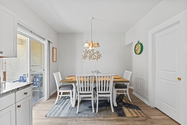 dining room featuring an inviting chandelier, a textured ceiling, and light wood-type flooring