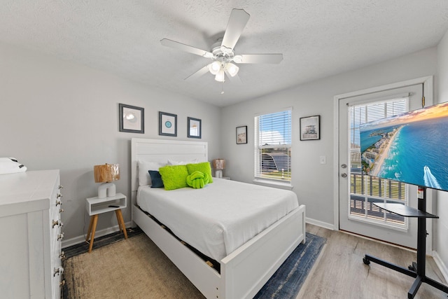 bedroom with access to exterior, a textured ceiling, light hardwood / wood-style floors, and ceiling fan