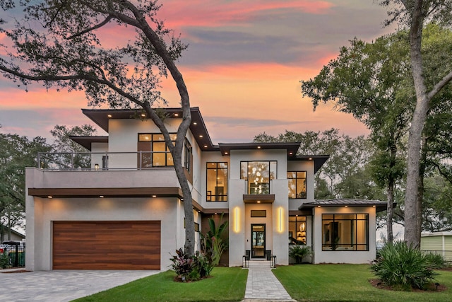 contemporary house featuring a lawn, a garage, and a balcony