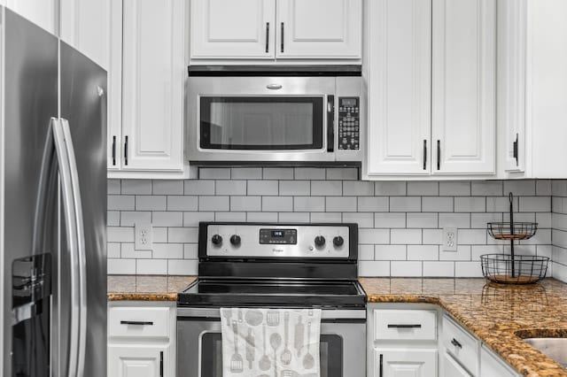 kitchen with white cabinetry, backsplash, appliances with stainless steel finishes, and dark stone counters