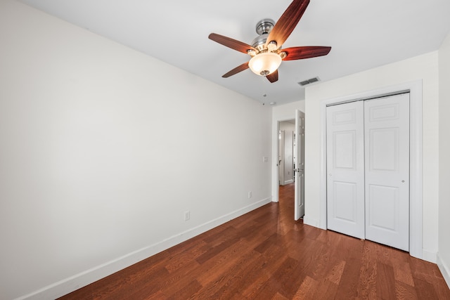 unfurnished bedroom with dark hardwood / wood-style flooring, a closet, and ceiling fan