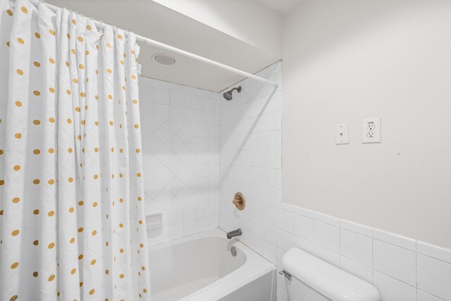 bathroom featuring toilet, tile walls, and shower / tub combo