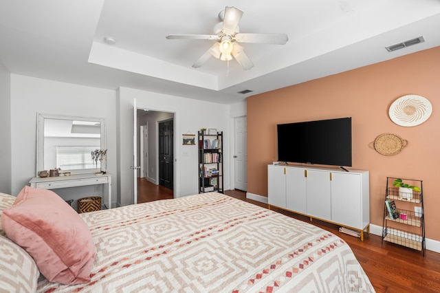 bedroom with a raised ceiling, ceiling fan, and dark hardwood / wood-style flooring