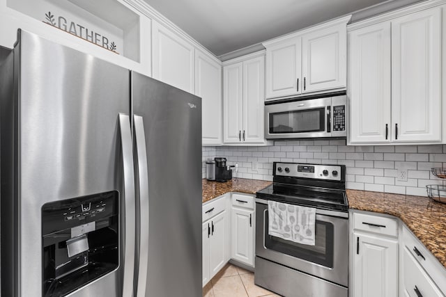 kitchen with light tile patterned floors, tasteful backsplash, dark stone countertops, white cabinets, and appliances with stainless steel finishes