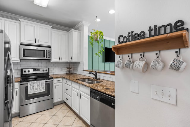 kitchen featuring dark stone counters, white cabinets, sink, light tile patterned flooring, and stainless steel appliances