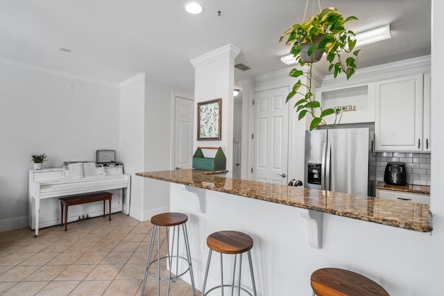 kitchen featuring white cabinets, decorative backsplash, dark stone countertops, light tile patterned floors, and stainless steel fridge with ice dispenser