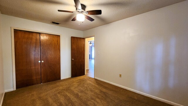 unfurnished bedroom with a textured ceiling, carpet flooring, a closet, and ceiling fan