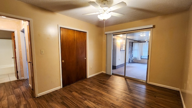 unfurnished bedroom featuring dark hardwood / wood-style floors, a textured ceiling, and ceiling fan