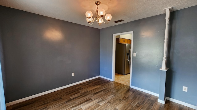 unfurnished room featuring hardwood / wood-style floors, a textured ceiling, and a chandelier