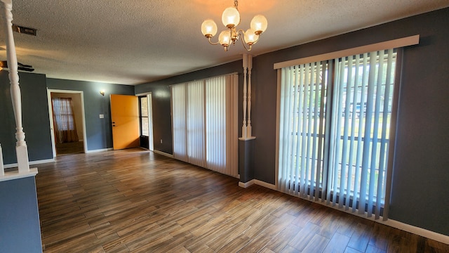 unfurnished room featuring a textured ceiling, a notable chandelier, and hardwood / wood-style flooring