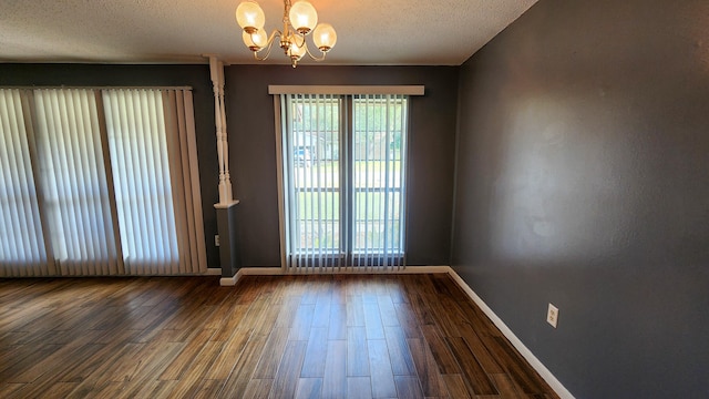 empty room with an inviting chandelier, hardwood / wood-style floors, and a textured ceiling