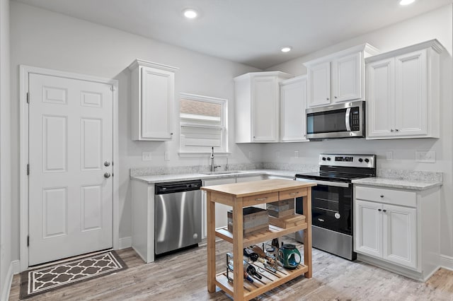 kitchen with light hardwood / wood-style flooring, white cabinets, and appliances with stainless steel finishes