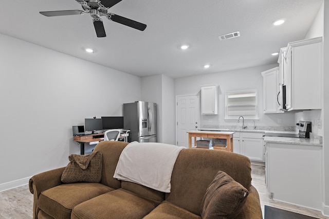 living room with ceiling fan, sink, and light wood-type flooring