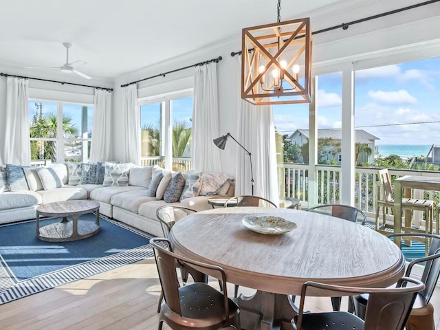 sunroom featuring a water view and ceiling fan with notable chandelier