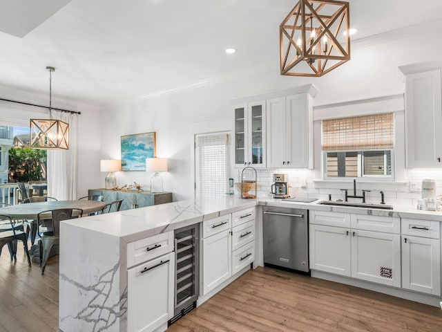 kitchen with sink, light wood-type flooring, white cabinetry, decorative light fixtures, and stainless steel dishwasher