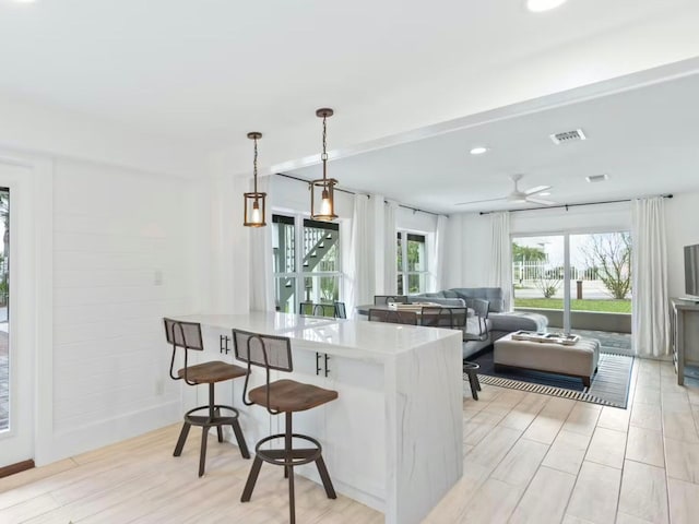 kitchen with a breakfast bar, pendant lighting, light hardwood / wood-style floors, and ceiling fan