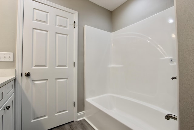 bathroom featuring hardwood / wood-style flooring, vanity, and bathing tub / shower combination