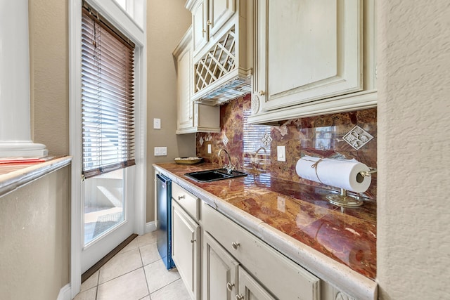 kitchen with backsplash, sink, light tile patterned floors, and dishwasher