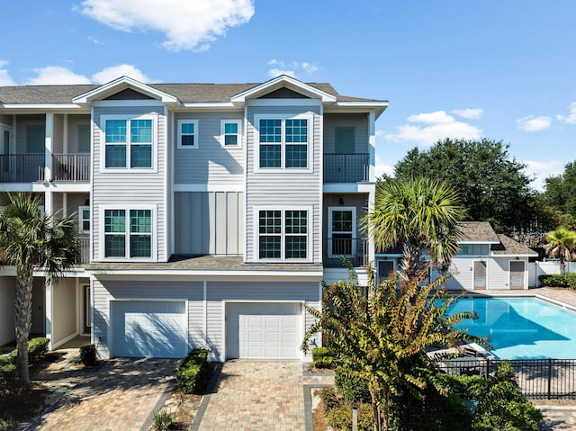 view of front of house featuring a balcony, a garage, and a fenced in pool